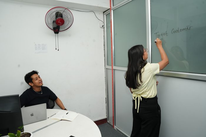 A member writing on the glass whiteboard in the Kapuche cabin at Stratex